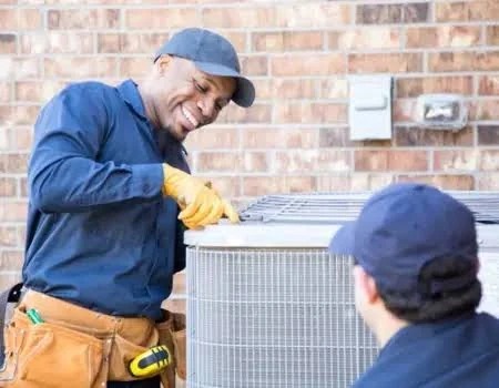 Two technicians working together on an outdoor cooling unit