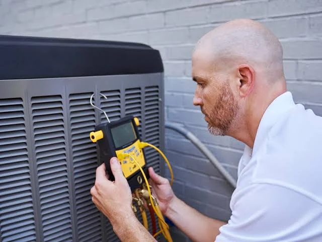 Technician using a clamp meter to test an outdoor HVAC unit