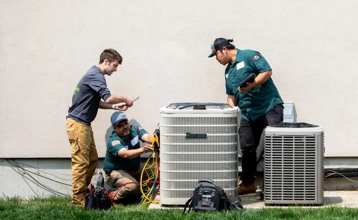 Three technicians inspecting outdoor air conditioning equipment