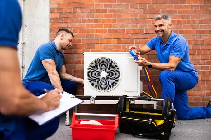 HVAC technicians inspecting a mini-split outdoor unit using pressure gauges